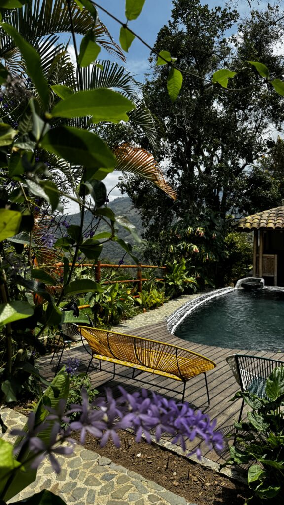 Blühende Pflanzen und Blumen am Zaun des Pools von AUEN Posada Andina mit Sitzbänken im AUEN Posada Andina – Pioniere der Touristik Lisa & Tobias Haarmeyer im Valle del Cauca
