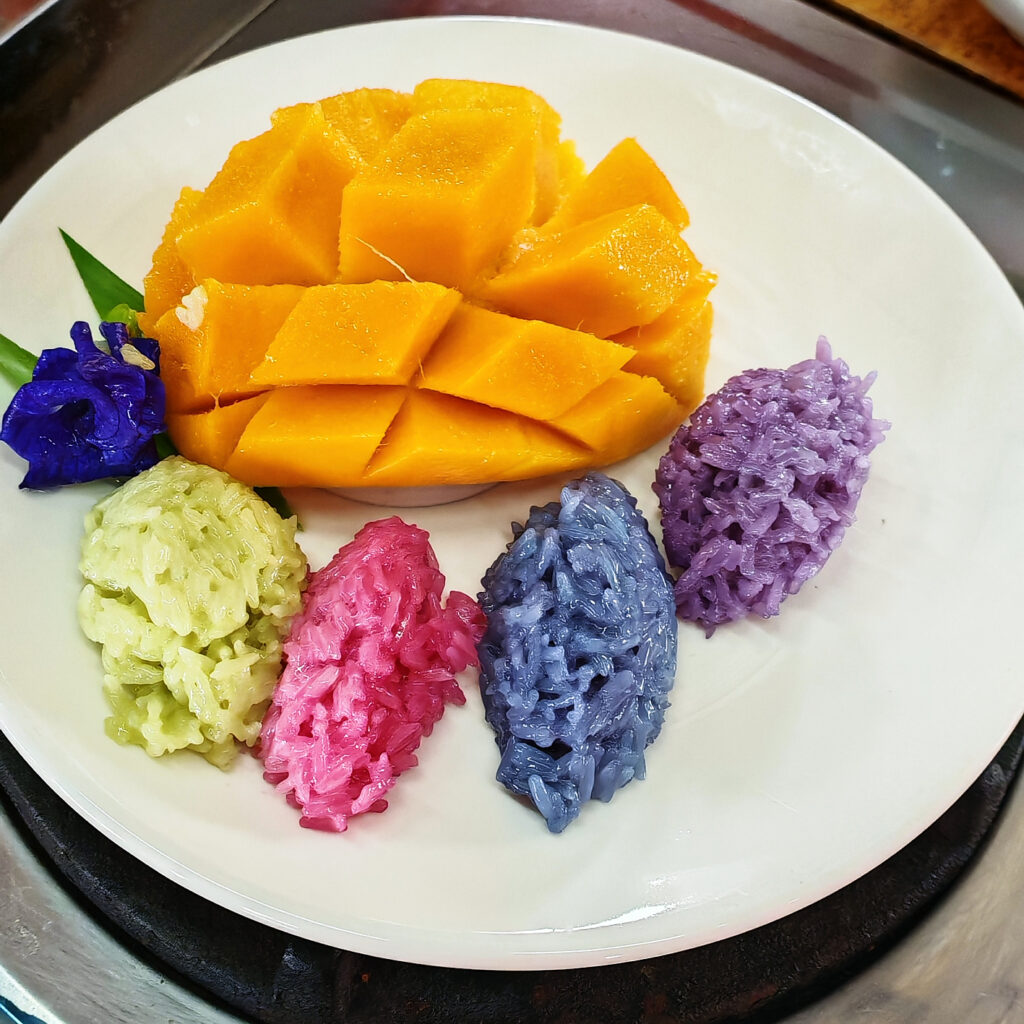 Thailands bekannteste Nachspeise: Mango und bunter Reis angerichtet auf einem Teller
